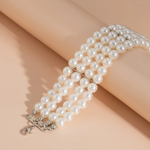 Detalle de pulsera de perlas de tres capas con cierre de mosquetón plateado y separadores