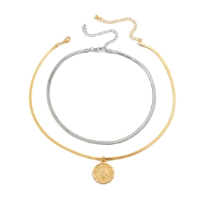 Close-up of layered snake chains with a gold Italian coin pendant on a white surface