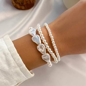 Detalle de pulseras de perlas barrocas de varias capas sobre fondo de tela de seda crema