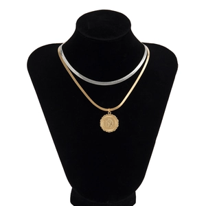 Detail of layered gold and silver snake chains with a vintage Italian coin pendant