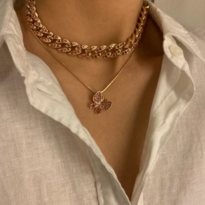 Nahaufnahme der goldenen Panzerkette und Schlangenkette mit pinkfarbenem Schmetterlingsanhänger