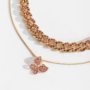 Nahaufnahme der goldenen Panzerkette und Schlangenkette mit rosa Schmetterlingsanhänger