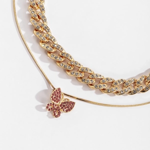 Detail der goldenen Gliederkette und Schmetterlingsanhänger mit weißen Strasssteinen