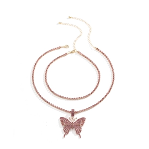 Detailaufnahme einer zweilagigen Goldkette mit einem großen rosa Kristall Schmetterling