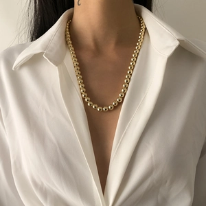 Nahaufnahme einer hochglänzenden goldenen Perlenkette, getragen von einem Model