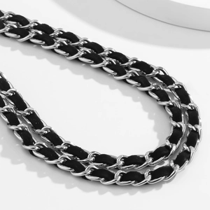 Détail d'une double chaîne argentée avec ruban de velours noir tressé à travers les maillons