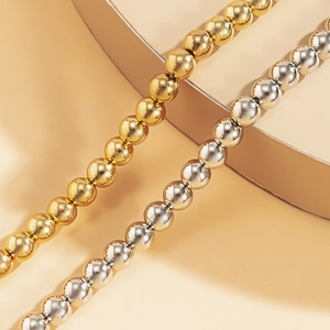 Detailansicht polierter Gold- und Silberkugeln an minimalistischen Metall-Schlangenhalsketten