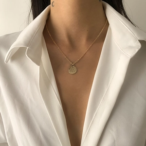 Nahaufnahme des minimalistischen Goldmünzen-Anhängers mit Textur an einer Gliederkette