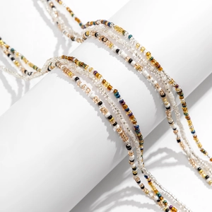 Detail view of multi-layered colorful seed bead waist chains on a white cylinder