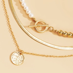 Detail der mehrlagigen Goldkette mit Perlen, Schlangenkette und Münzanhänger-Charm