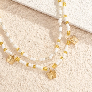 Detail of beaded waist chain with white seed beads and golden butterfly charm