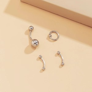 Primer plano de set de piercing en acero inoxidable pulido con anillo para el ombligo