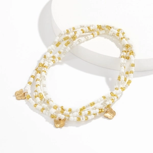 Detailed macro view of white seed bead body chain with gold butterfly charms