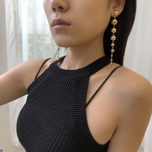Close-up of polished gold bead drop earrings worn by a model in soft natural light