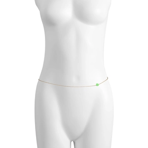 Dettaglio di una sottile catena dorata per la vita con un piccolo ciondolo a fiore verde su busto