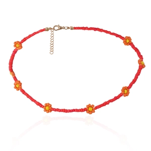 Detail van bohemien rode kralenketting met gele bloemaccenten en gouden sluiting