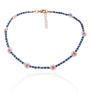 Detail van kralenketting met madeliefjes, blauwe kralen en gouden verstelbare sluiting
