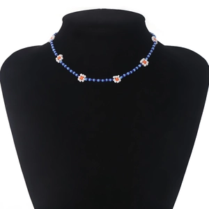 Detail van een boho kralenketting met blauwe kralen en madeliefjes op een zwarte buste