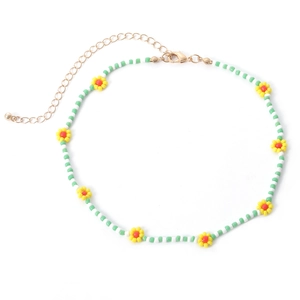 Detail van kralenketting met madeliefjes, groene kralen en gouden verstelbare karabijnsluiting