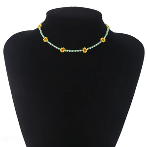 Detail van boheemse madeliefjes kralenketting met groene kralen en bloemmotieven