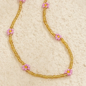 Close-up of handmade gold bead body chain featuring pink and yellow floral charms