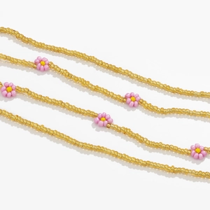 Detail of bohemian gold waist chain featuring delicate pink daisy flower beads