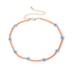Detail van bohemien oranje kralenketting met blauwe bloemen en een gouden sluiting