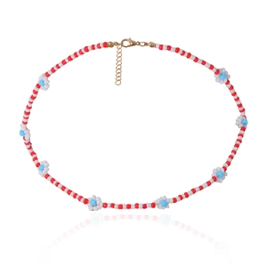 Detail van handgemaakte kralenketting met madeliefjes en een gouden karabijnsluiting