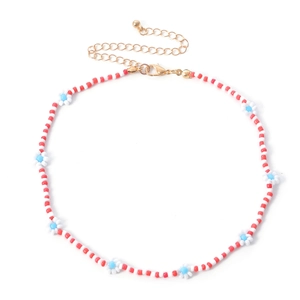 Detail van handgemaakte kralenketting met rood-witte kralen en kleine madeliefjespatronen