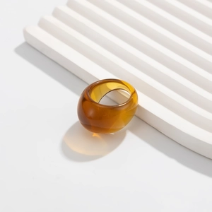Nahaufnahme eines bernsteinfarbenen Acrylrings mit glänzendem Finish auf weißem Grund
