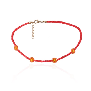 Detail van rode kralenketting met gele madeliefjes en een gouden metalen sluiting