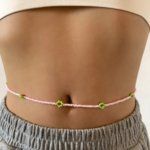 Detail of pink seed bead body chain featuring small green and red beaded flowers on waist