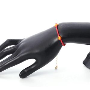 Detail van rode kralenarmband met madeliefjes en een gouden verstelbare verlengketting