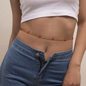 Detail of bohemian gold bead waist chain with red flowers on a model wearing jeans