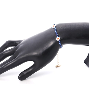 Detail van kralenketting met witte madeliefjes op zwart model handdisplay
