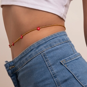 Detail of bohemian daisy waist chain with brown beads and red flowers on blue jeans