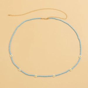 Detail view of light blue beaded waist chain with small white daisy flower accents and gold clasp