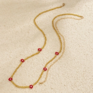 Macro detail of Bohemian beaded waist chain with red daisy flowers and gold clasp