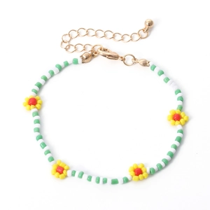 Detail van bohemien madeliefje kralenketting met groene witte kralen en gouden sluiting