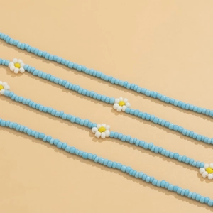 Detail of bohemian blue seed bead body chains with white daisy flower patterns