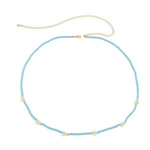 Detail of bohemian blue seed bead body chain with small daisy flowers and gold clasp