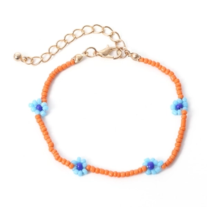Detail van handgemaakte oranje kralenketting met blauwe madeliefjes en gouden sluiting