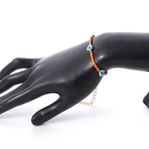 Detail van de kleurrijke kralenketting met madeliefjes en oranje en blauwe kralen op model