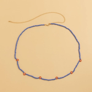 Detail of bohemian blue seed bead body chain with orange daisy flowers and golden clasp