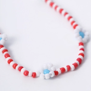 Macrodetail van een Boheemse kralenketting met rood-witte kralen en kleine madeliefjes