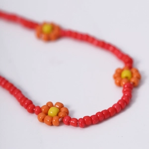 Macro-opname van een kleurrijke kralenketting met rode kralen en oranje madeliefjes