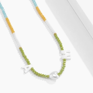 Detail van de bohemien kleurrijke kralenketting met letters en zilveren hartbedel