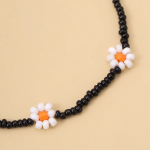 Detail van boheemse zwarte kralenketting met delicate witte madeliefjesbloem bedeltjes