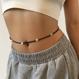Detail of bohemian black beaded waist chain with small white and orange daisy flower accents