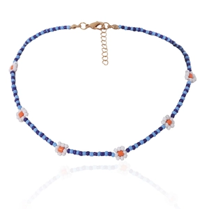 Detail van kralenketting met blauwe kralen en witte madeliefjespatronen
